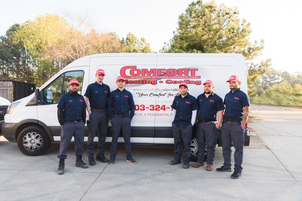 Uniformed company techs standing in front of a branded service vehicle