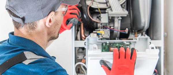 Technician with red gloves examines complex machinery